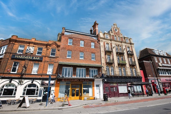 A street view with buildings, including a bar named 'MARINERS BAR' and a shop called 'GALLEGOT'S pin pin.'