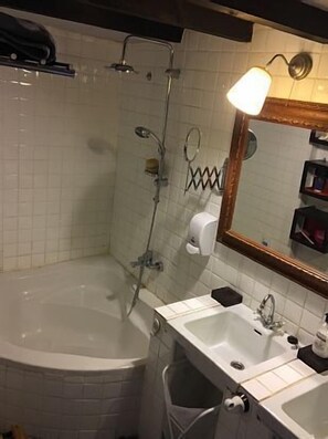 Een badkamer met een bad, twee wastafels, een spiegel en een handdoekhouder.
