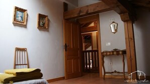 A room with wooden beams, a door leading to another room, a small table, and two framed pictures on the wall. - Casa de la Maestra for 10 people (Barbolla)