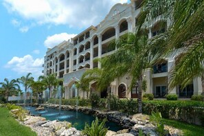 A multi-story hotel with a pool, palm trees, and a rocky landscape. - The Landmark Resort Of Cozumel (Cozumel)