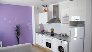 A compact kitchen with white cabinets, a built-in microwave, a stainless steel range hood, and a front-loading washing machine. - Cozy apartment in Muelle Deportivo Morro Jable, pets are allowed. (Morro Jable)