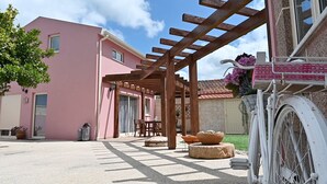 A pink building with a pergola, outdoor seating, and a bicycle. - Escondidinho Houses - Casa da Eira (Bajouca, Leiria)