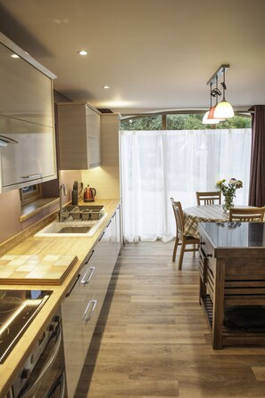 Une cuisine moderne dotée de plans de travail en bois, d’appareils électroménagers en acier inoxydable et d’un coin repas avec une table et des chaises.