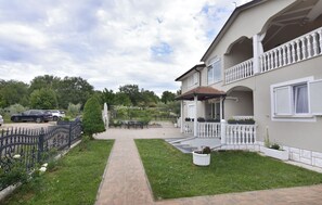 En boligejendom med en belagt sti, en balkon med gelænder og en have.