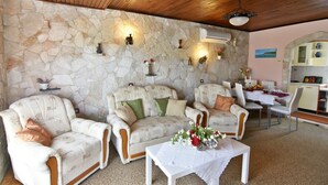 Ein gemütliches Wohnzimmer mit Steinwänden, einem Kamin und einem Essbereich mit Tisch für zwei Personen.