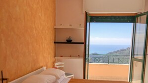 A bedroom with a bed, a nightstand, a dresser, and a view of the sea through a balcony. - House Joseph with beautiful view and private parking (Ravello)