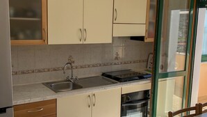 A kitchen with wooden cabinets, a stainless steel sink, a built-in oven, and a dining area with a table and chairs. - House Joseph with beautiful view and private parking (Ravello)