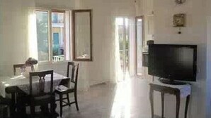 A room with a dining table, chairs, a television, and a window.