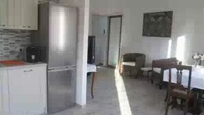 A compact kitchen with white cabinets and a built-in refrigerator. There is a dining area with a table and chairs.
