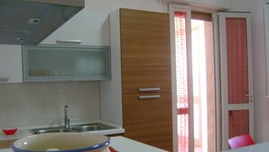 Una cocina con un lavamanos, un armario de madera y un ventanal con cortina.