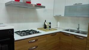 Una cocina con gabinetes blancos, estufa a gas, lavamanos y encimera de madera.