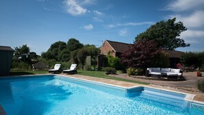 A swimming pool with two lounge chairs and a patio area with a sofa. - Tastefully Renovated Countryside Cottage with Swimming Pool near Tenterden (High Halden)