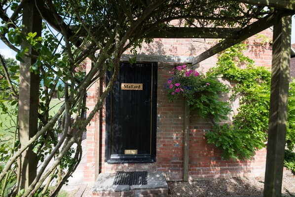 A black door with a sign reading "Mallard" in a brick building with greenery around. - Tastefully Renovated Countryside Cottage with Swimming Pool near Tenterden (High Halden)