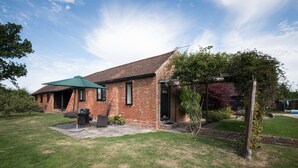 A brick house with a tiled roof, a covered patio area, and a garden with potted plants. - Tastefully Renovated Countryside Cottage with Swimming Pool near Tenterden (High Halden)
