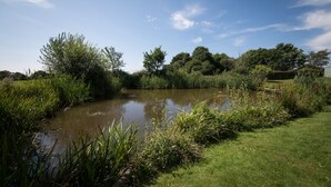 A tranquil pond surrounded by lush greenery and trees, with a clear sky above. - Tastefully Renovated Countryside Cottage with Swimming Pool near Tenterden (High Halden)