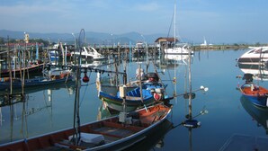 A marina with various boats docked, calm water, and a clear sky.