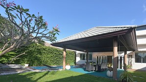 A covered outdoor area with a pool, lounge chairs, and a patio table.