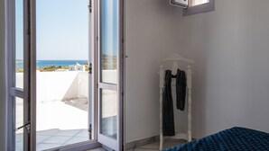 A room with a large sliding glass door leading to a balcony, a white wardrobe, and a bed with a blue cover. - Villa Paros - Archipelagos Villas with Pool close to the sea (Naousa Paros)