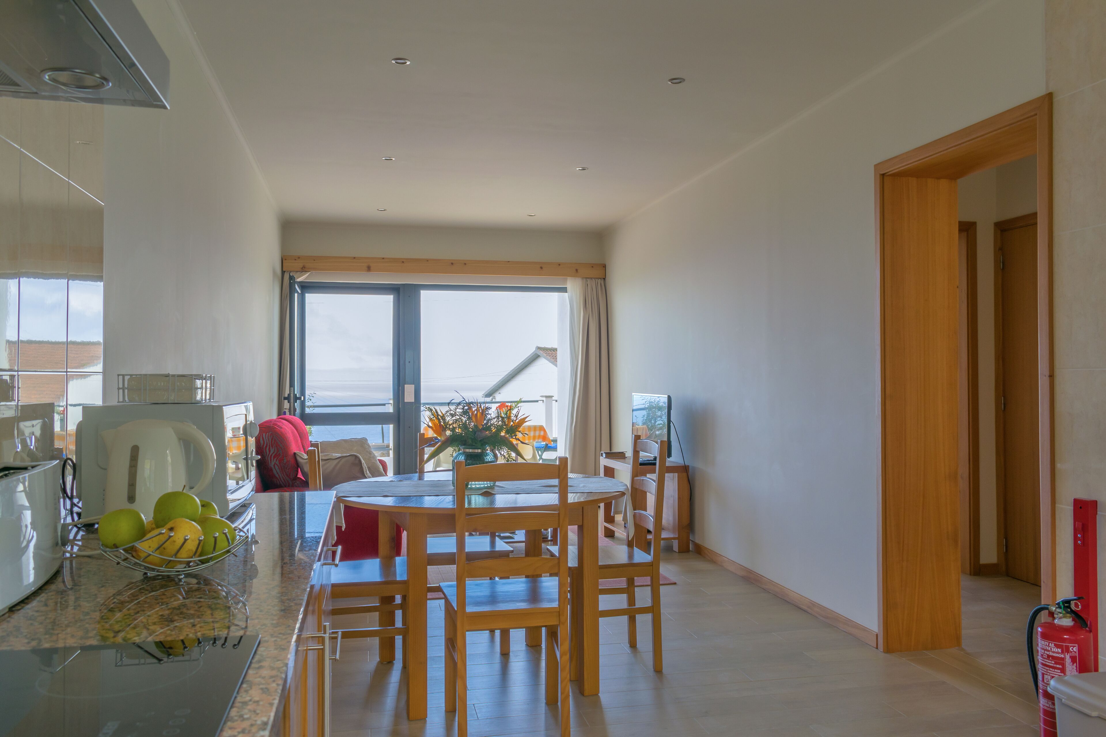 A modern kitchen with a dining area, a view of the sea, and a fire extinguisher.