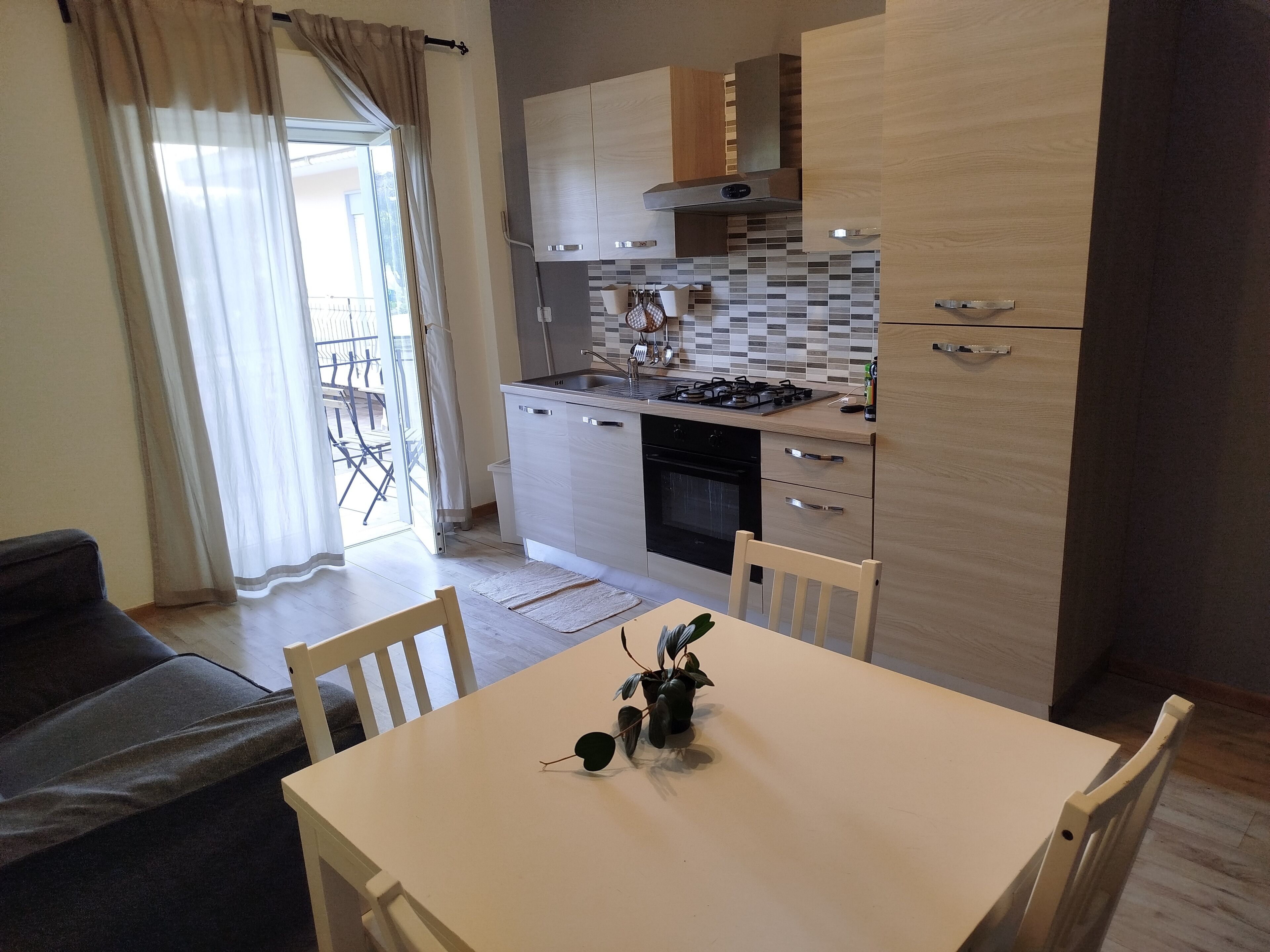 A compact kitchen with a dining table, chairs, and a sofa.