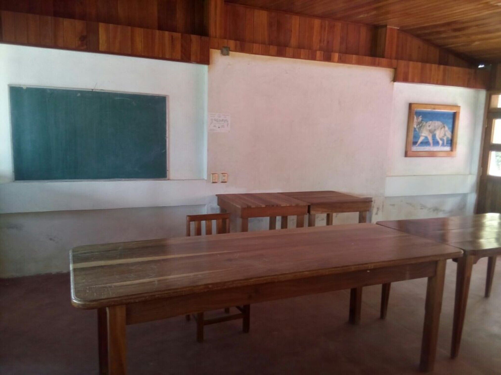 A classroom with wooden desks and a chalkboard.