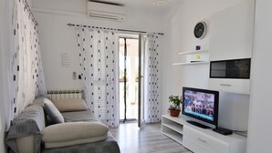 A modern living room with a sofa, TV, and a potted plant. - Comfortable apartment in Valizza-Umag, surrounded by greenery, air-conditioned (Valica)