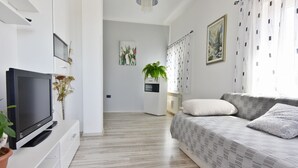 A modern living room with a flat-screen TV, a sofa, a coffee table, and a potted plant. - Comfortable apartment in Valizza-Umag, surrounded by greenery, air-conditioned (Valica)