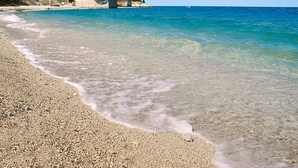 A pebble beach with clear water, a bridge, and buildings in the background. - Comfortable apartment in Valizza-Umag, surrounded by greenery, air-conditioned (Valica)