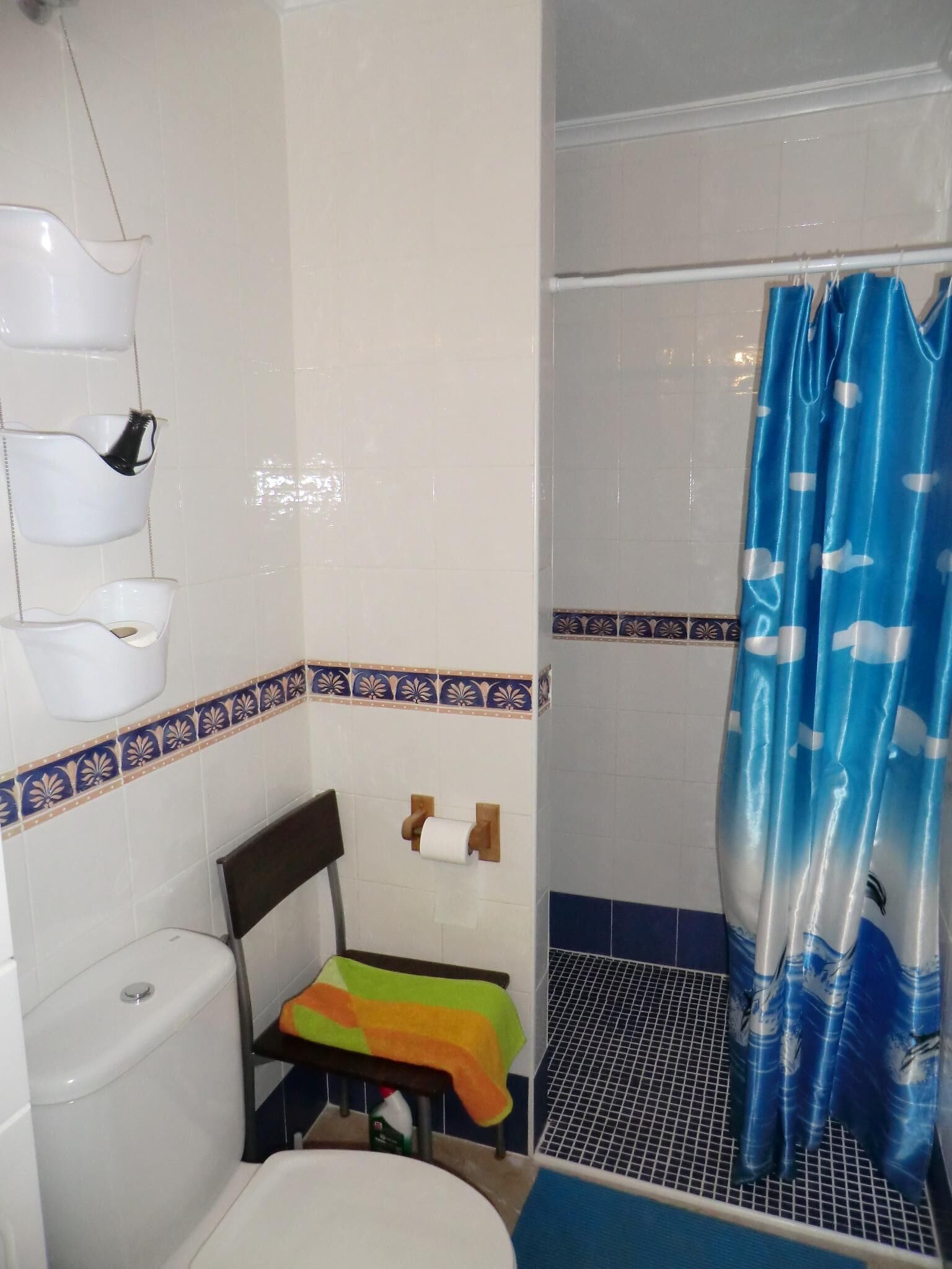 A bathroom with a toilet, a shower with a blue curtain, and a sink with a soap dish.