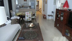 Une chambre d’hôtel comprenant un coin repas, un canapé, un meuble pour la télévision et un ventilateur de plafond.