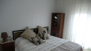 Une chambre à coucher avec un lit, une table de chevet, une lampe et une armoire en bois.