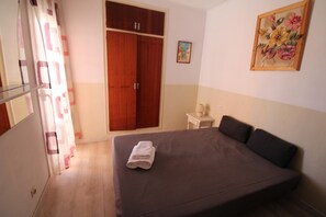Quarto com cama, guarda-roupa, um quadro e uma pequena mesa de cabeceira.