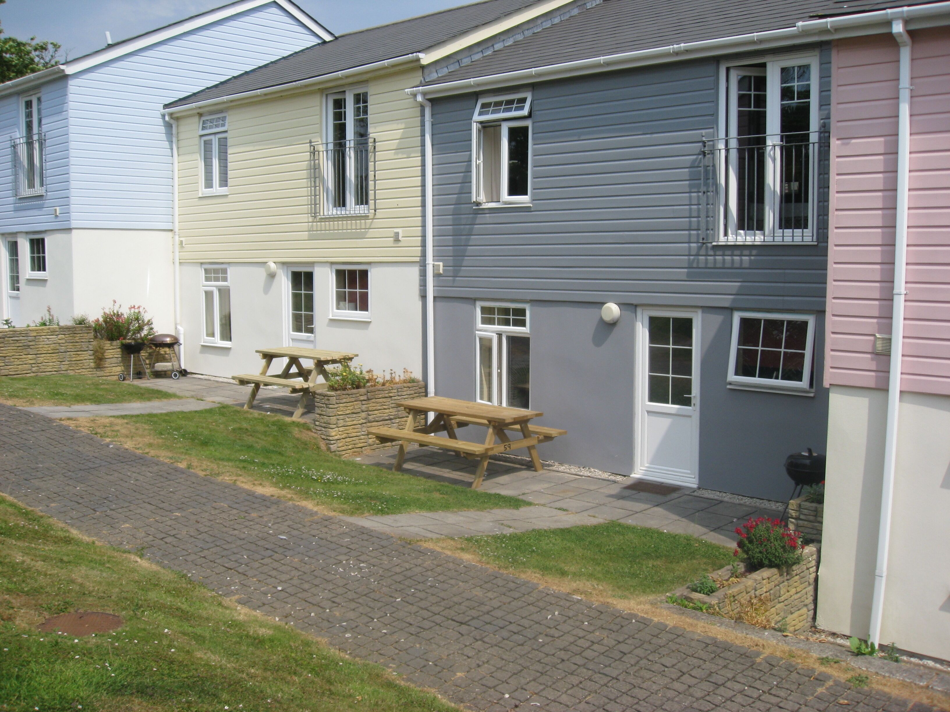 Une rangée de maisons aux couleurs vives, avec un chemin piétonnier et des tables de pique-nique.