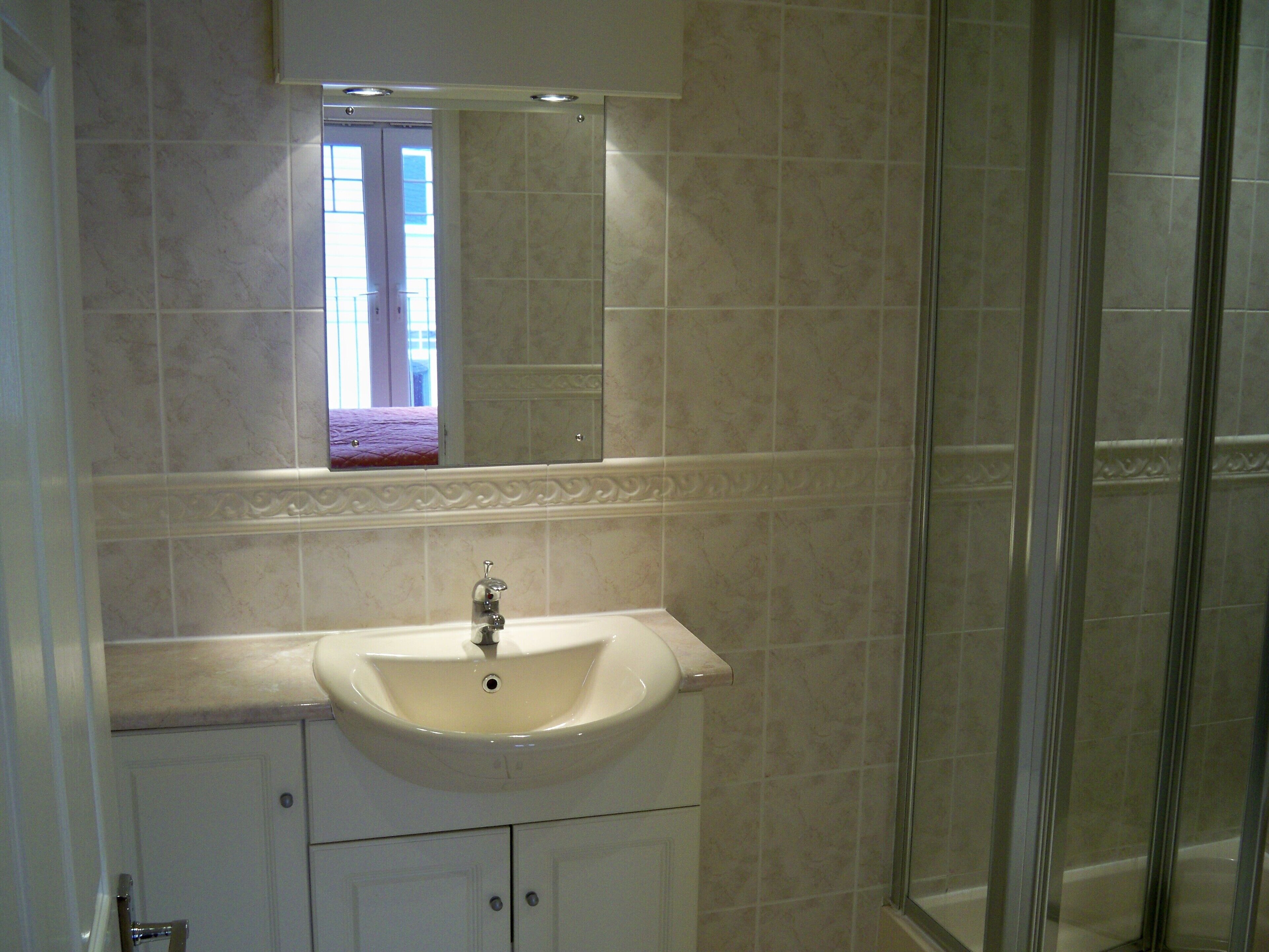Ein Badezimmer mit Waschbecken, Spiegel und Dusche.