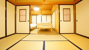 Ett traditionellt japanskt rum med tatamimattor på golvet, en futonmadrass, skjutdörrar och en taklampa.