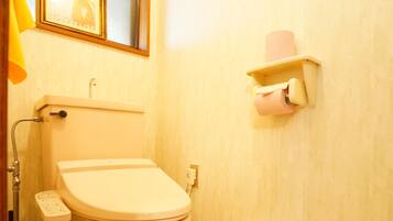 A bathroom with a toilet, a hand dryer, a towel rack, and a framed picture on the wall.