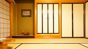 Ett traditionellt japanskt rum med tatamimattor på golvet, skjutdörrar och en liten dekorativ skulptur.
