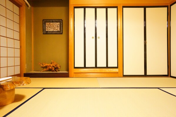 A traditional Japanese room with tatami flooring, sliding doors, and a small decorative sculpture.