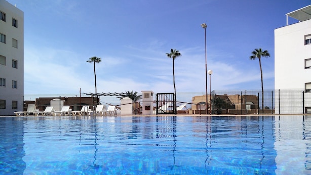 A clear swimming pool with lounge chairs and palm trees. - Cozy and comfortable, best location! Ideal for families. (Costa Adeje)