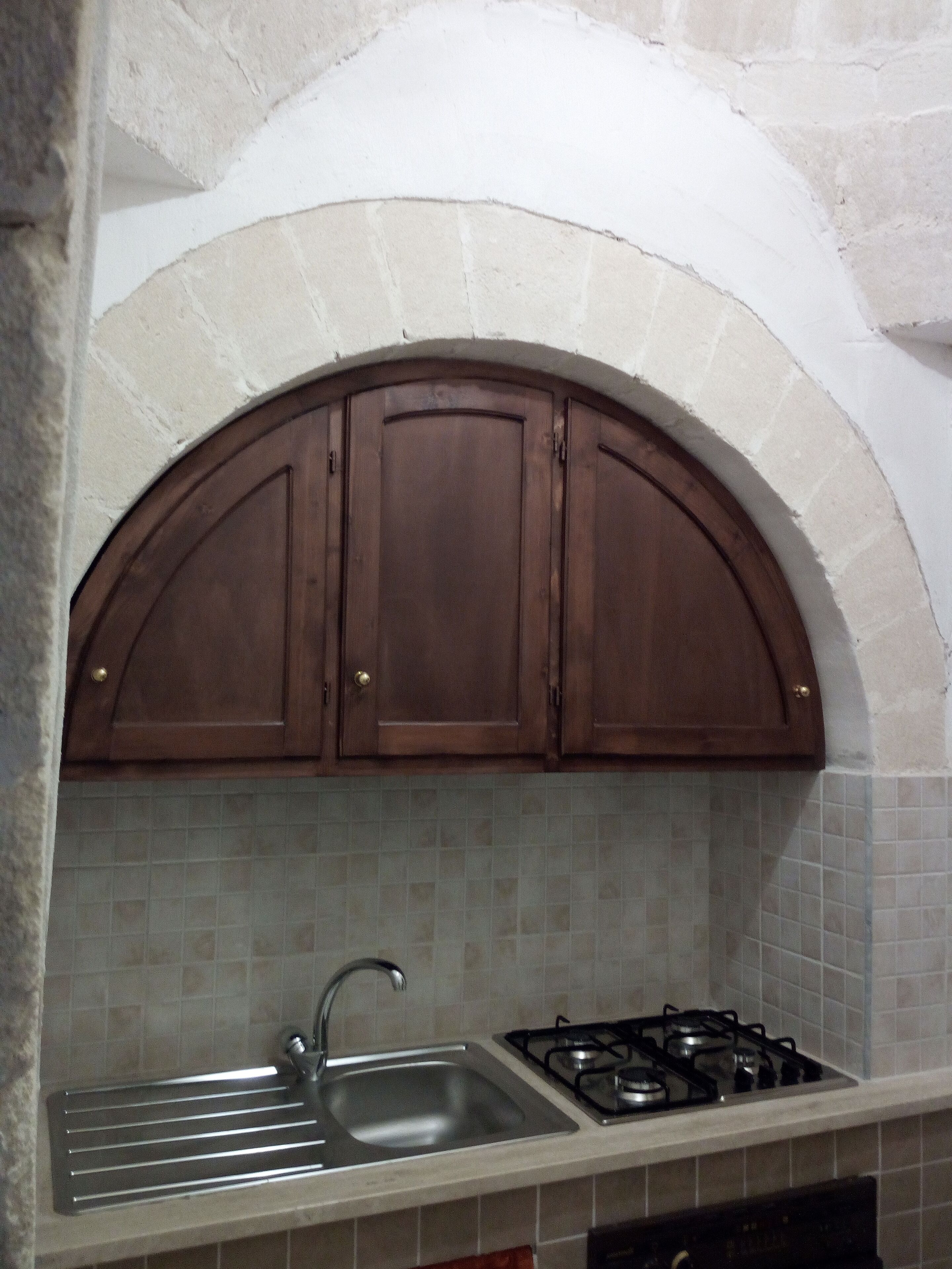 Una cocina con horno empotrado, un lavamanos y una estufa a gas.
