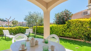 Eine Terrasse mit rundem Tisch, Stühlen und Essplatz im Freien.