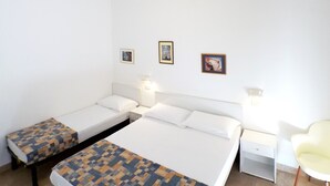 A hotel room with two single beds, a desk, a chair, and three framed pictures on the wall. - HOLIDAY RESIDENCE: sea and shopping within reach. (Lido degli Estensi)