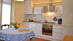 A compact kitchen with white cabinets, a stainless steel range, and a tiled backsplash.