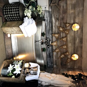 Bathroom features a large bathtub, metal sink, and a potted plant.