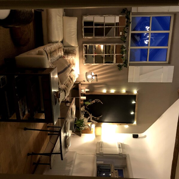 Relax in a serene space with a sofa, table, and plant, surrounded by a unique architectural design with exposed beams and a sloped ceiling.