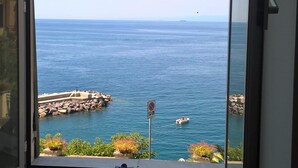 Une pièce dotée d’une grande fenêtre donnant sur une étendue d’eau, avec vue sur la mer et une côte rocheuse où se trouve un bateau.