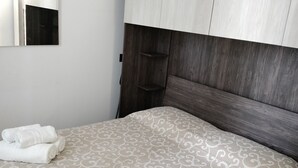 Un lit bien fait, avec une couvre-lit à motifs, une tête de lit en bois et un miroir au mur.