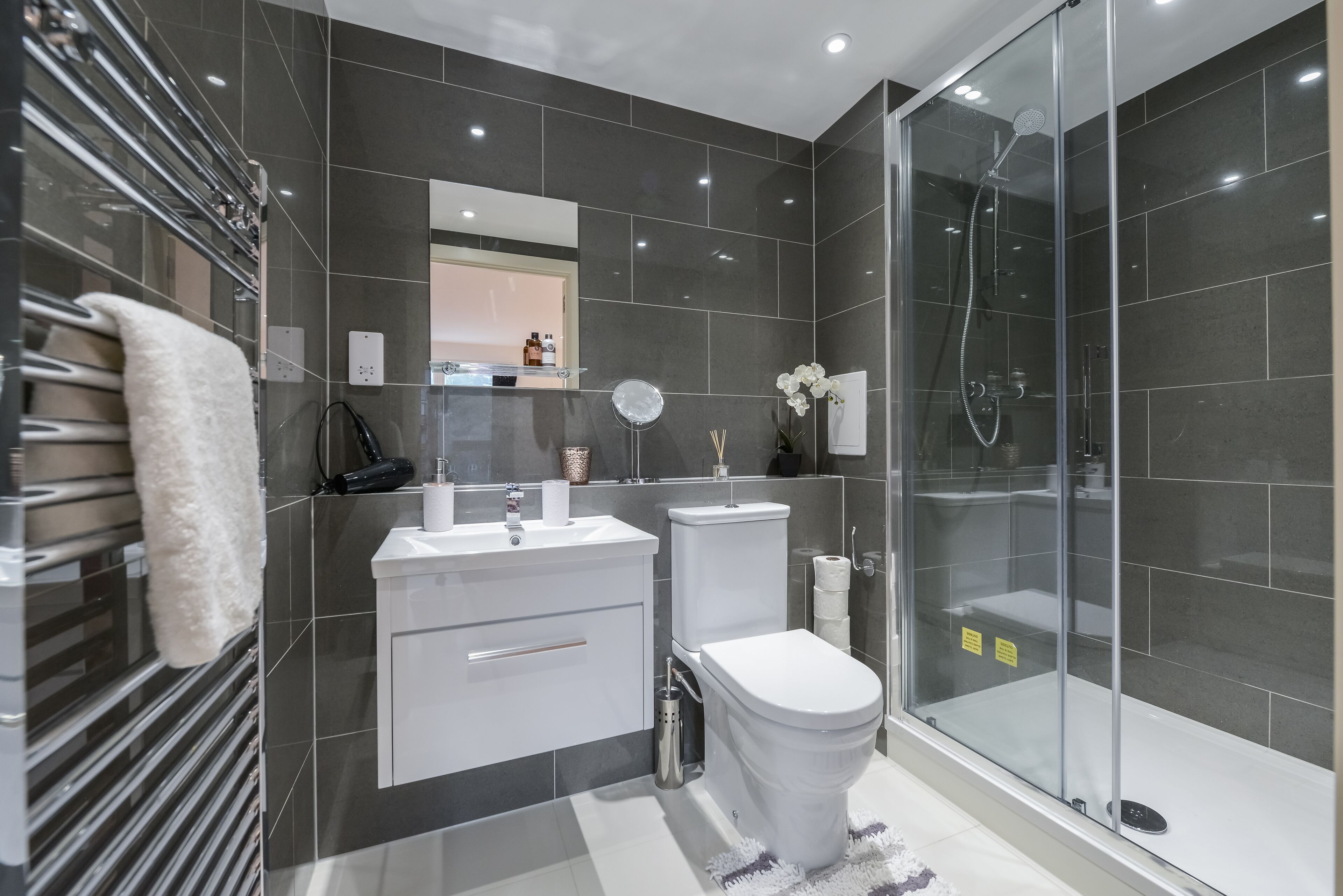 A modern bathroom with a glass shower enclosure, a white toilet, and a vanity with a mirror.