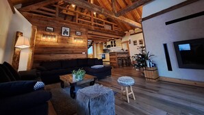 Un interior rústico con vigas de madera a la vista, un comedor de madera y un rincón de descanso acogedor.