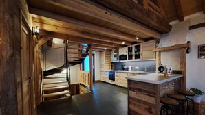 Un interior de madera con una zona de cocina, una escalera y una barra.